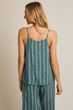 Woman wearing green and cream striped spaghetti strap top on gray background