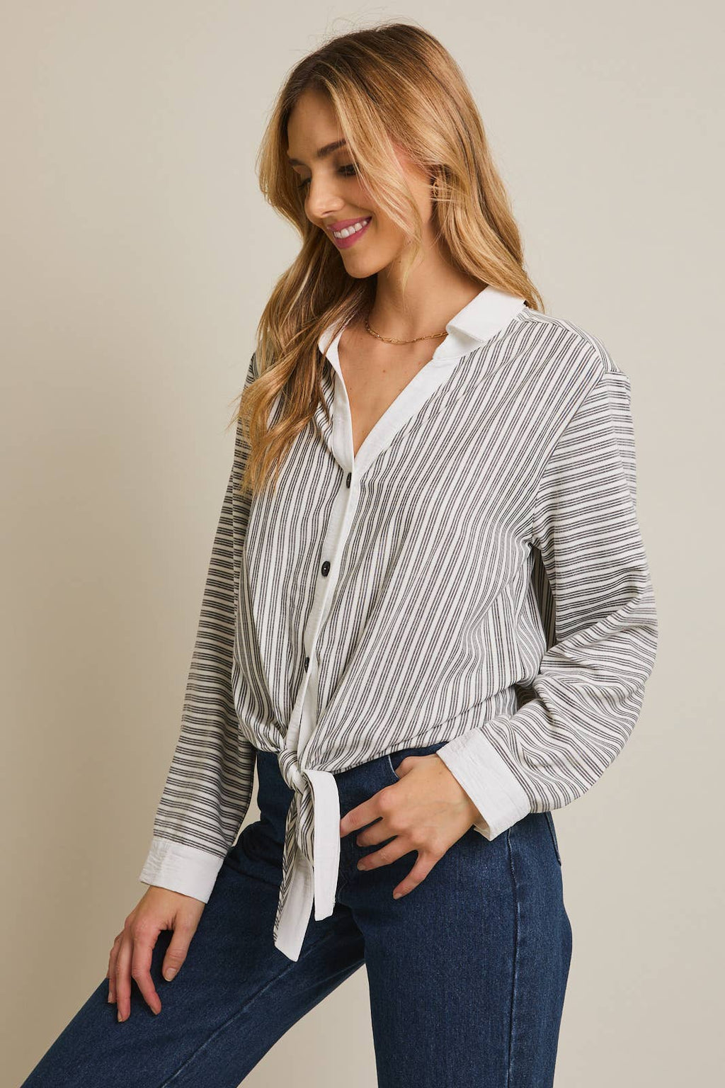Woman wearing a striped shirt and blue pants against a beige 