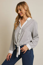 Woman wearing a striped shirt and blue pants against a beige 