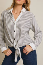 Woman wearing a striped shirt and blue pants against a beige 
