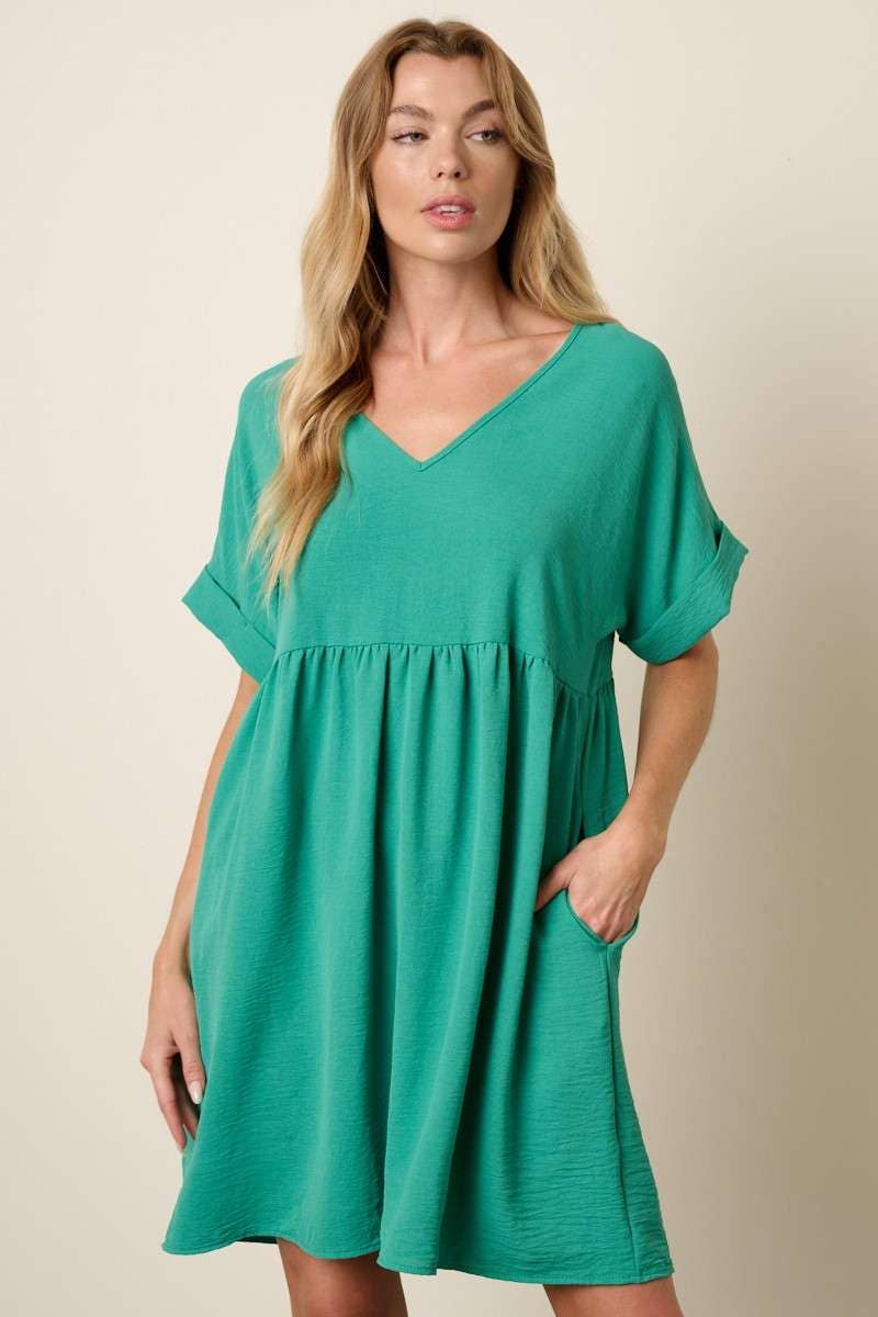 Woman wearing a green babydoll dress against a beige background