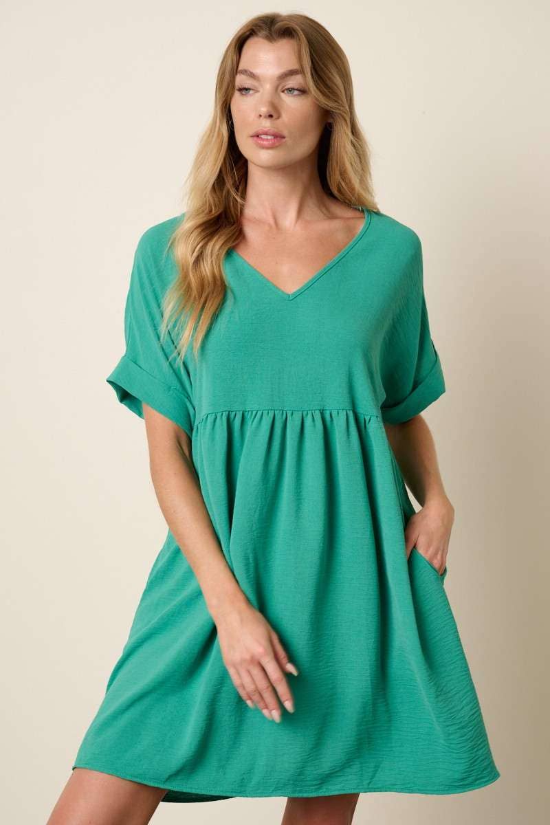 Woman wearing a green babydoll dress against a beige background