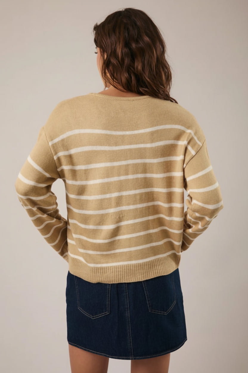 Back view of a woman wearing a tan and cream striped sweater with navy skirt against a plain background