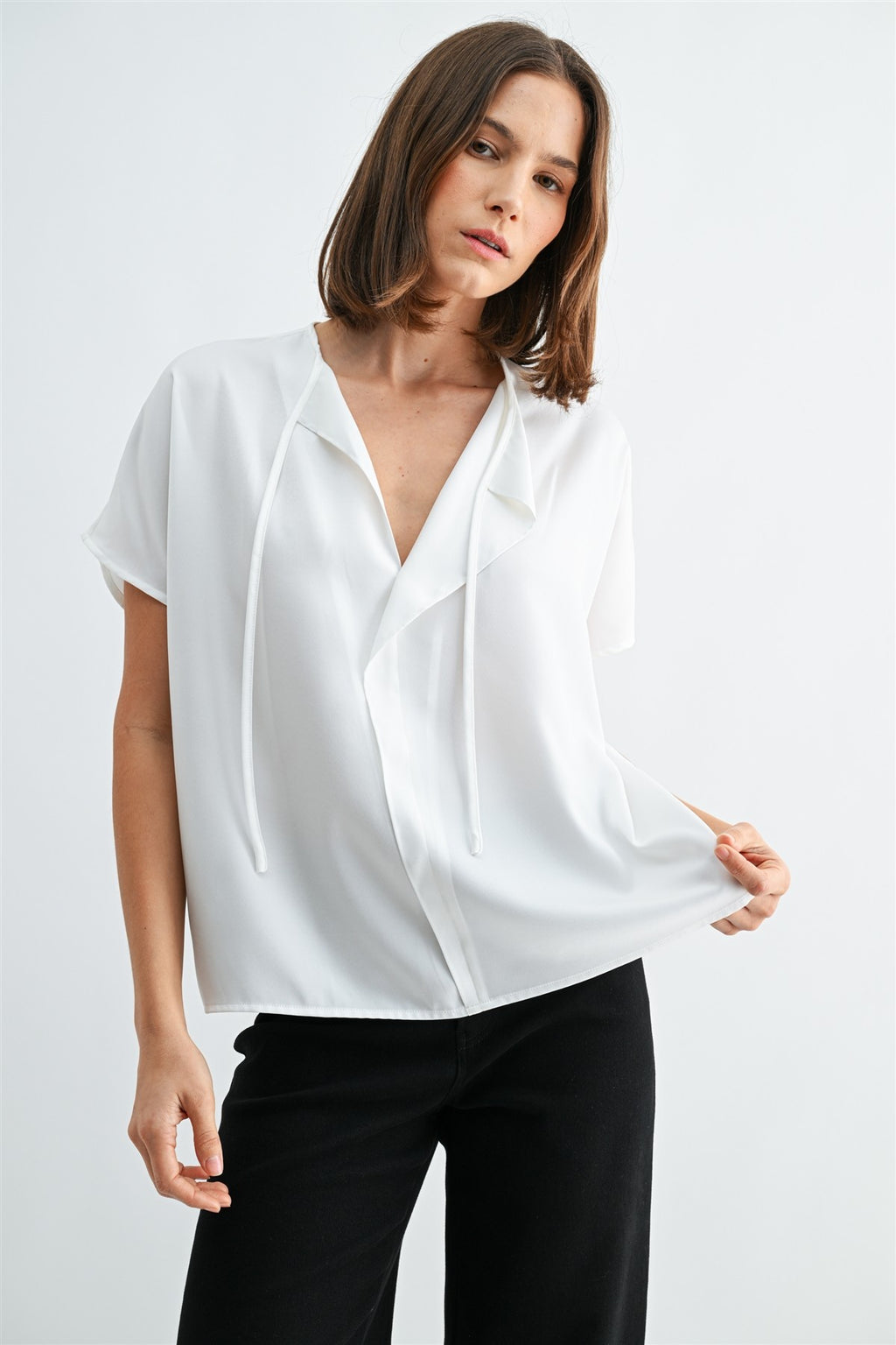 Woman wearing a white blouse with split neck on a plain background