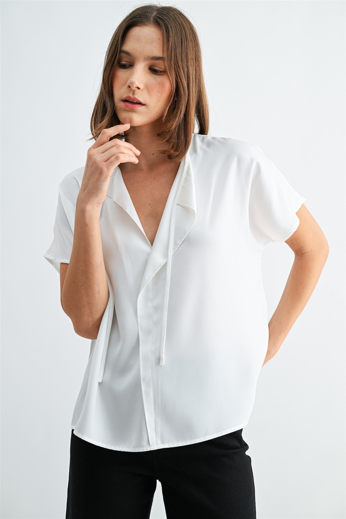 Woman wearing a white blouse with split neck on a plain background