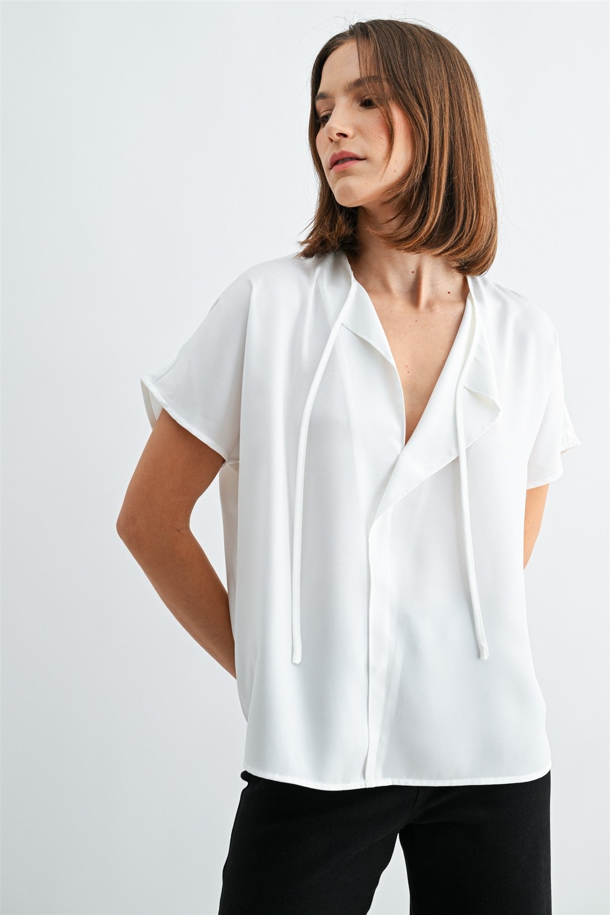 Woman wearing a white blouse with split neck on a plain background