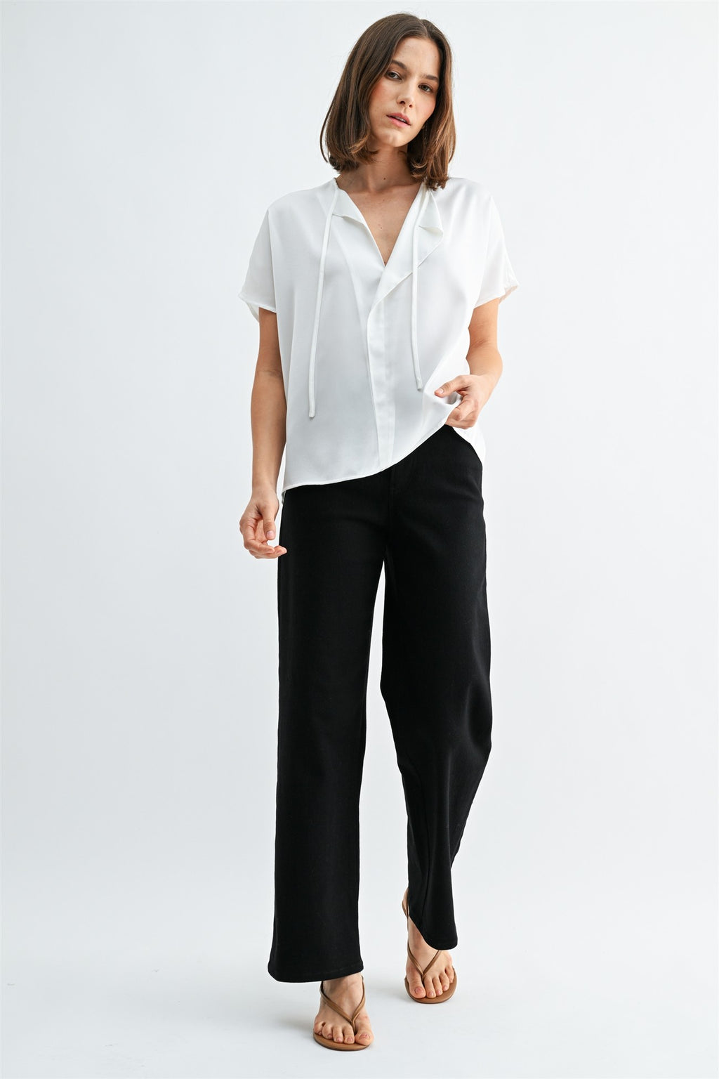 Woman wearing a white blouse with split neck on a plain background
