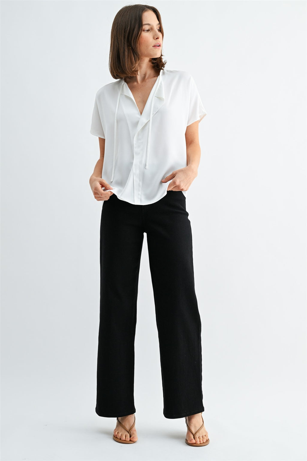 Woman wearing a white blouse with split neck on a plain background