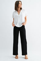 Woman wearing a white blouse with split neck on a plain background