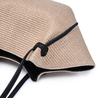 Natural straw bag with black strap on a white background