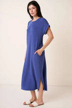 Woman wearing a royal blue midi dress on a plain background