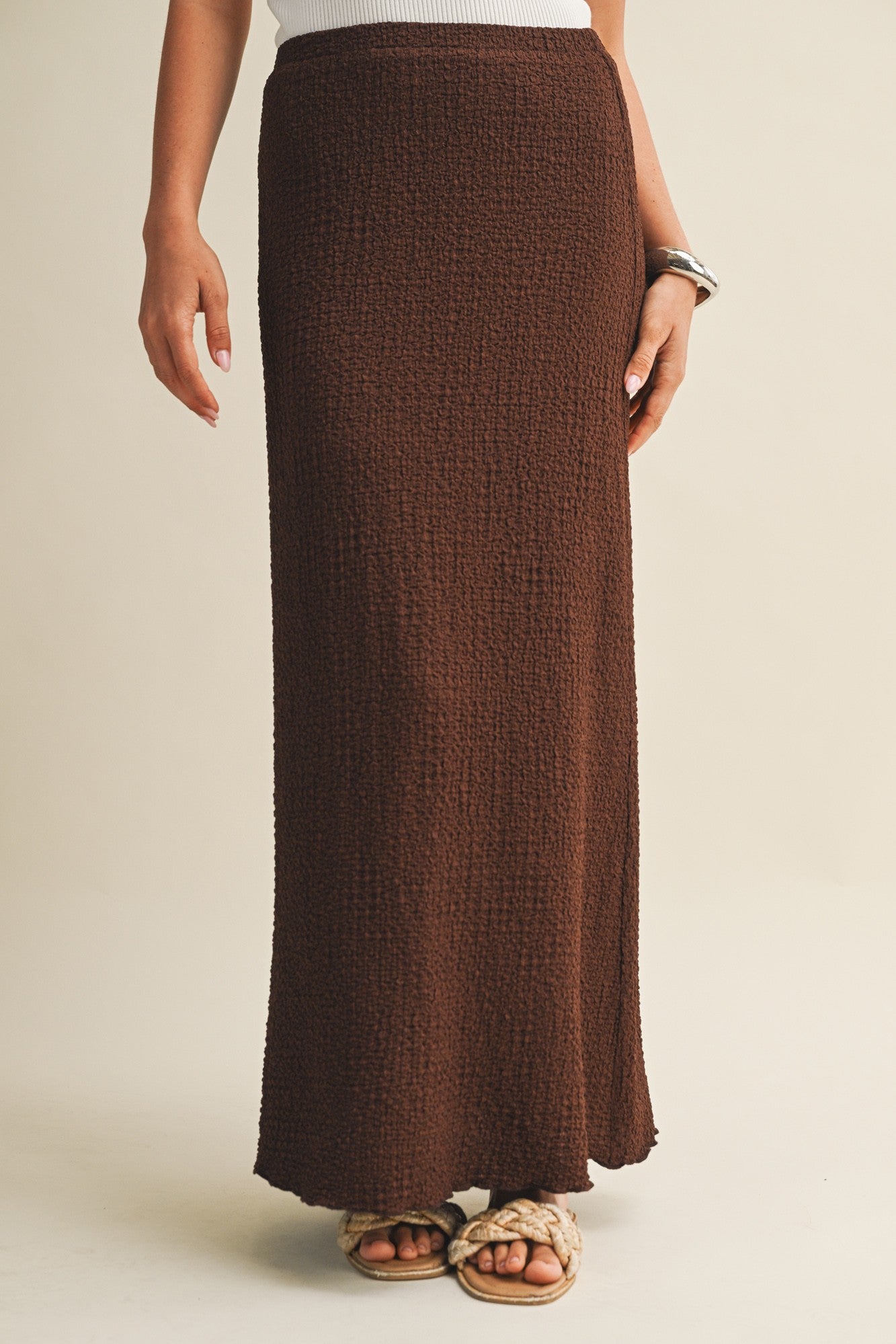 Brown bubble texture skirt worn by a woman on a beige background