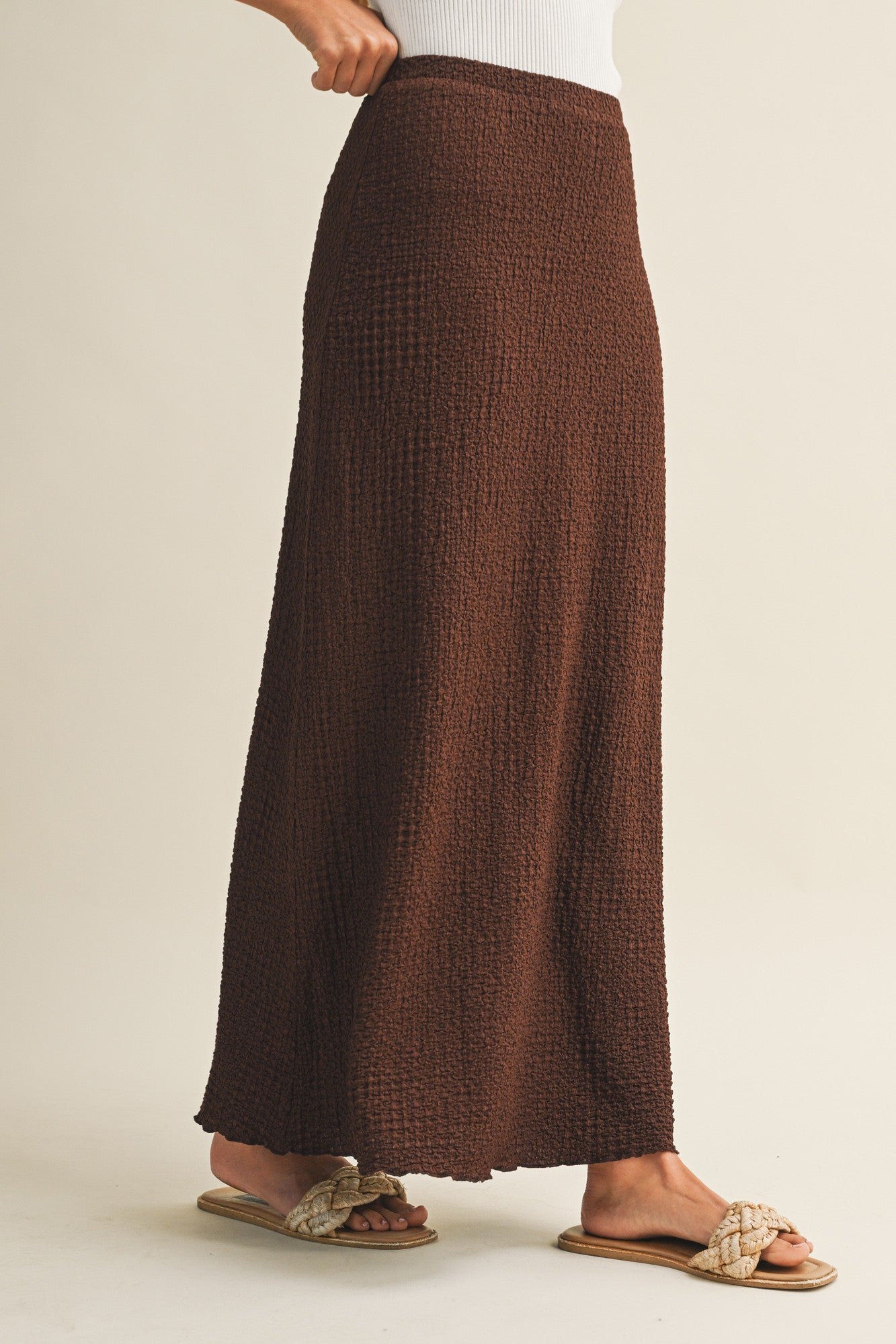 Brown bubble texture skirt worn by a woman on a beige background