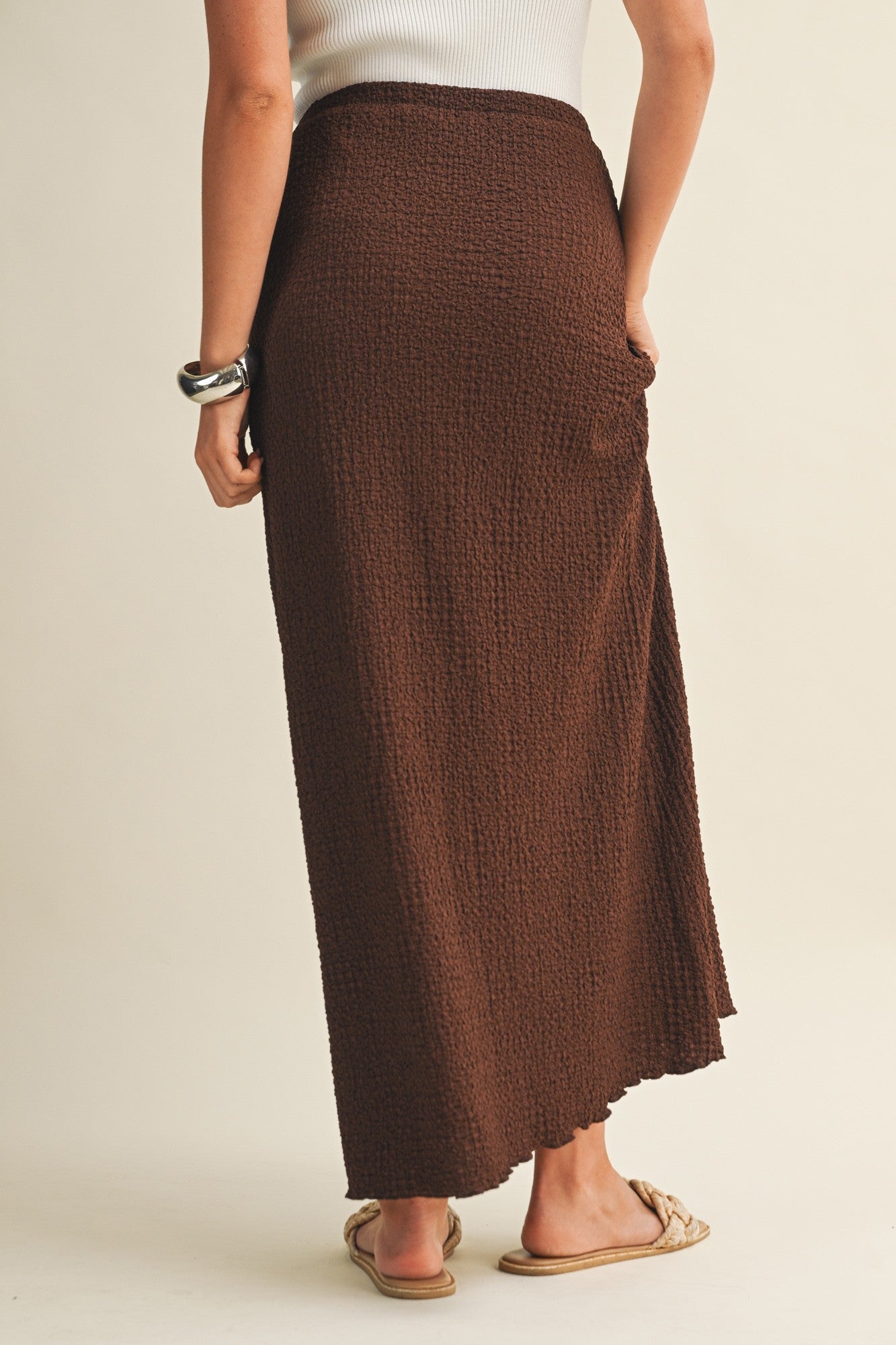 Back view of brown bubble texture skirt worn by a woman on a beige background