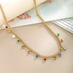 Gold chain necklace with colorful gemstones on a beige surface