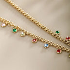 Bright colorful gemstone on a gold chain on a beige surface