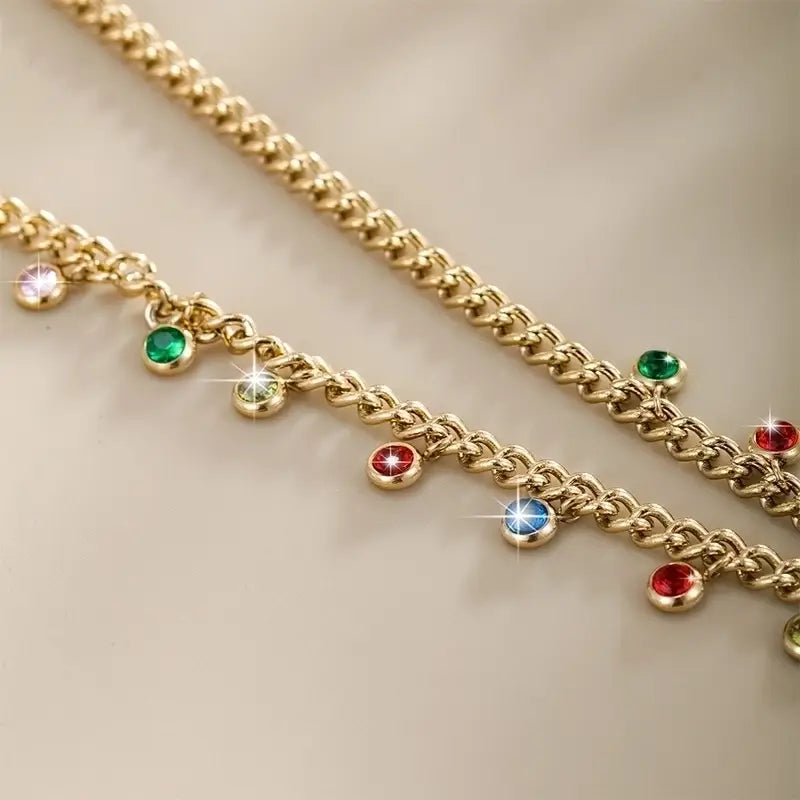Bright colorful gemstone on a gold chain on a beige surface