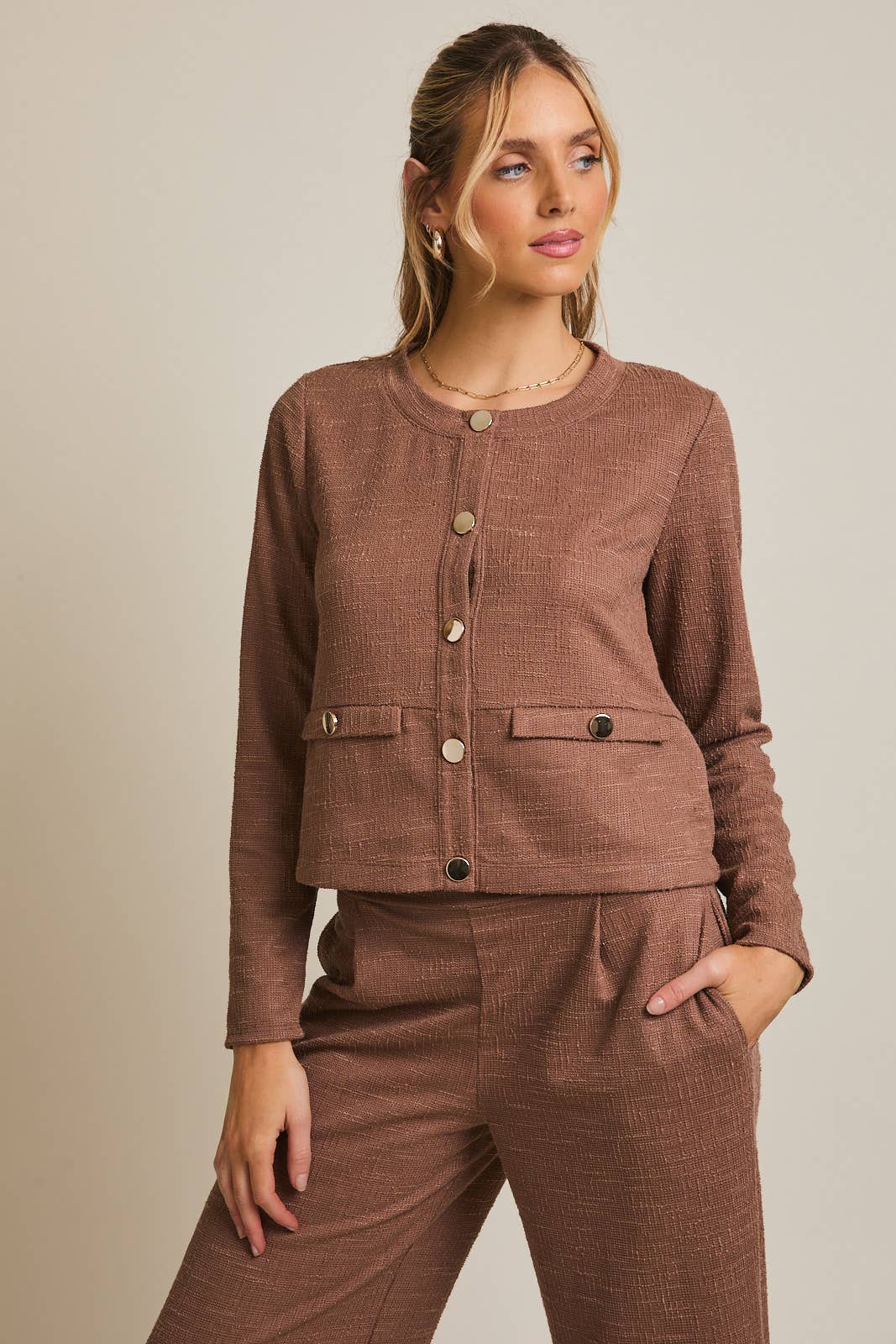 Woman wearing a brown boucle outfit against a beige background