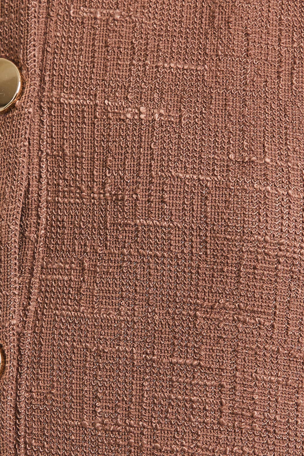 Close-up of  brown boucle fabric with a button detail