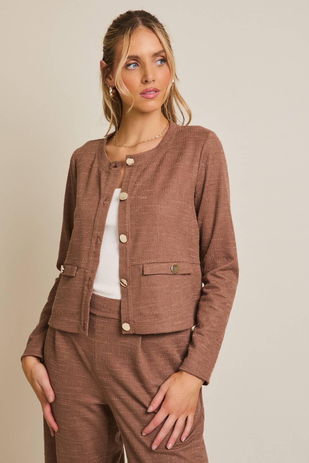 Woman wearing a brown textured outfit with a matching jacket and pants on a beige background