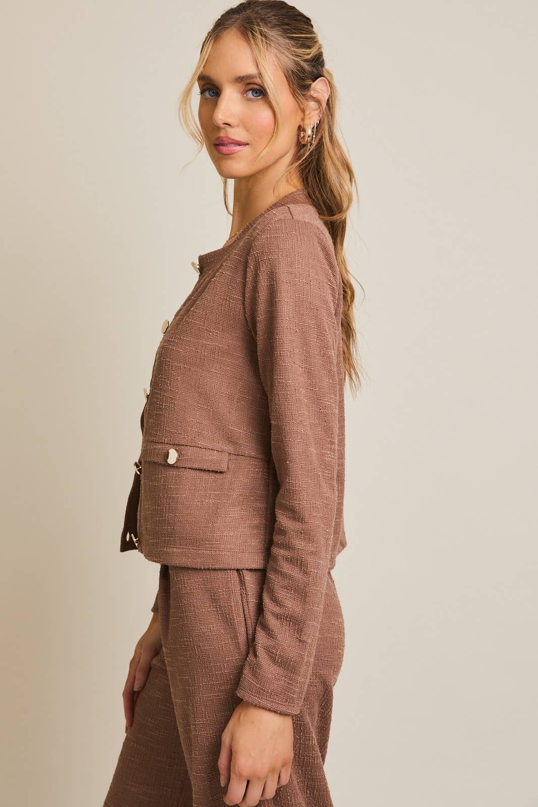 Woman wearing a brown boucle jacket against a beige background