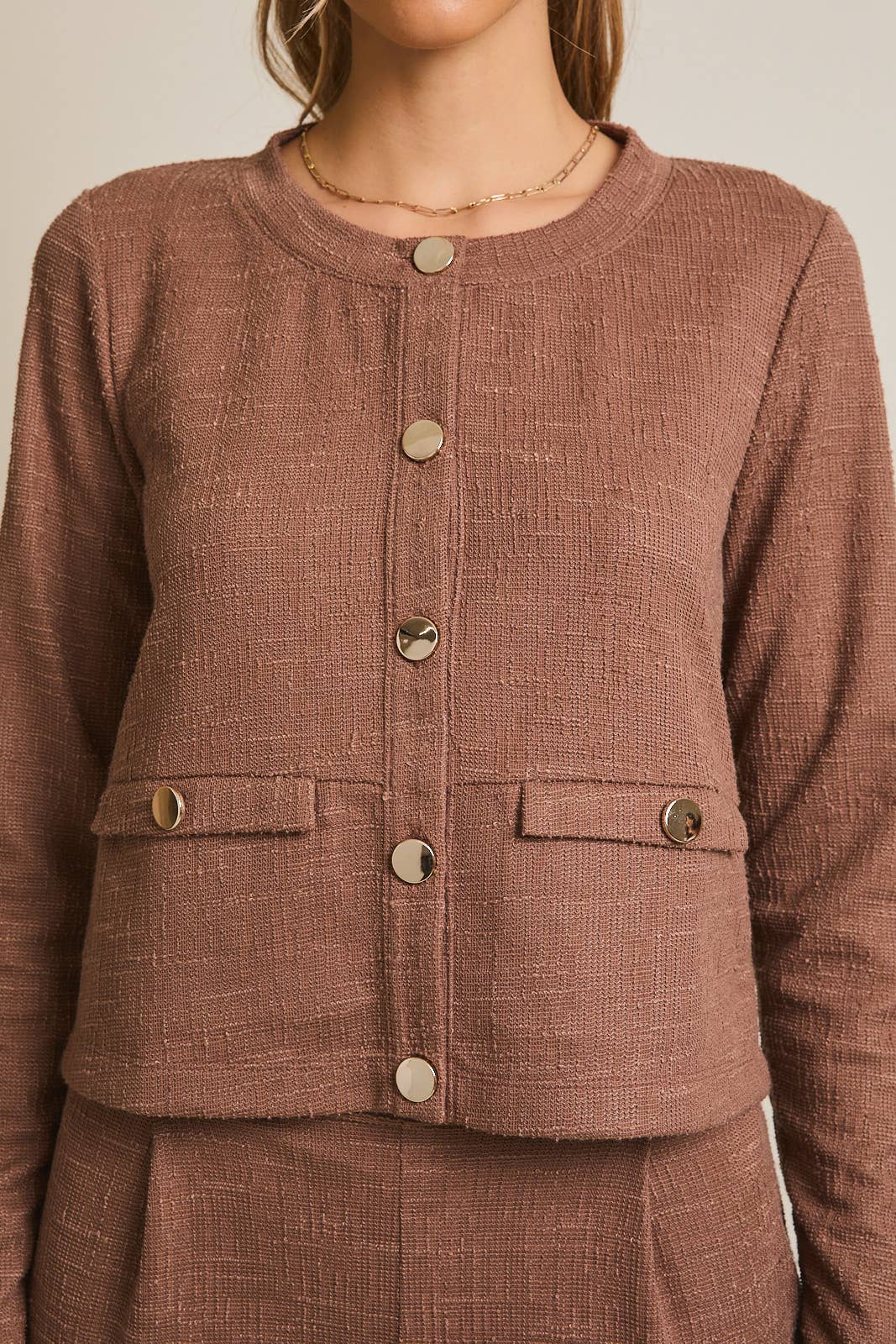 Brown boucle jacket with gold buttons on a neutral background