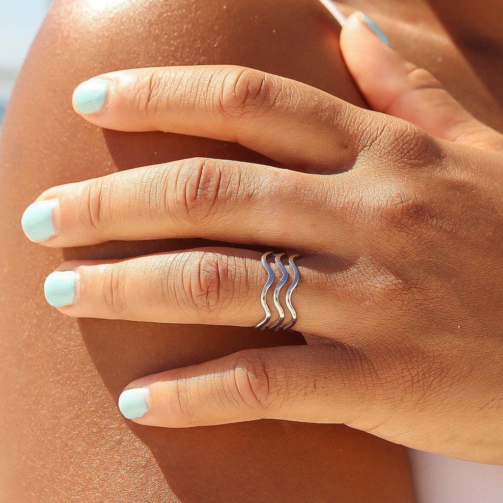 Close-up of woman wearing silver triple wavy ring.