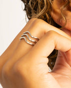 Close-up of woman wearing silver triple wavy ring.
