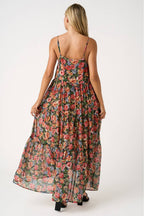 Back view of a woman wearing a floral tiered maxi dress on a white background