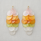 Colorful layered disc earrings on a light fabric background