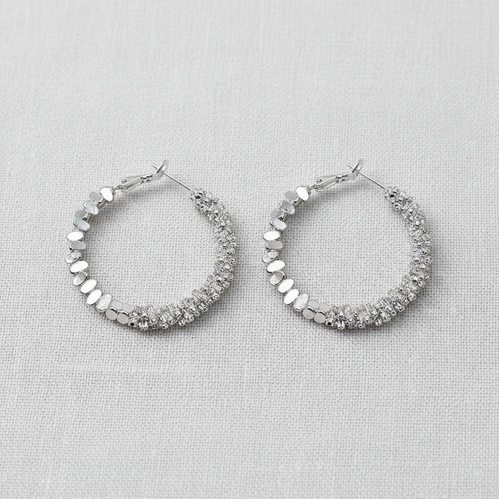 Pair of silver hoop earrings with texture on a light gray background