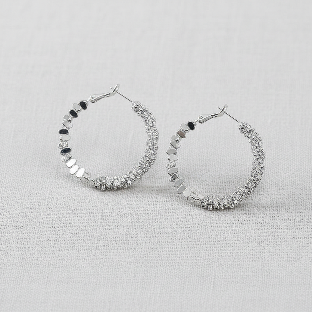 Pair of silver hoop earrings with texture on a light gray background