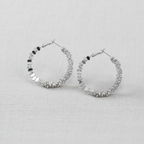Pair of silver hoop earrings with texture on a light gray background
