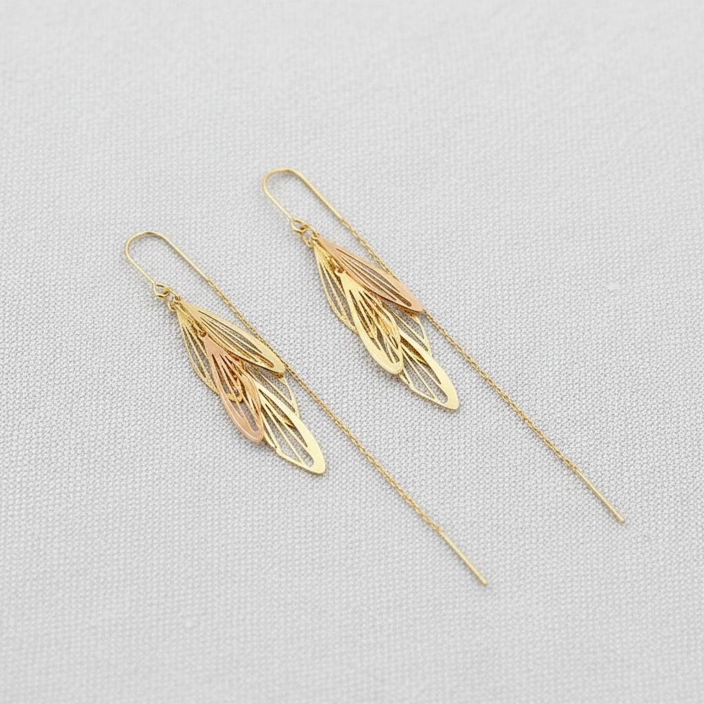 Gold leaf-shaped threader earrings on a light gray background