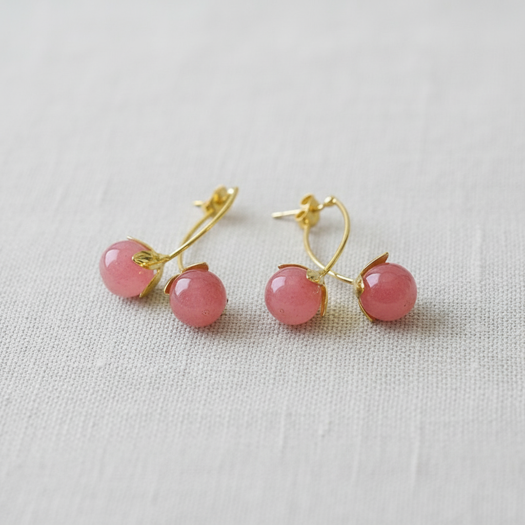 Pair of pink ball earrings with gold accents on a light gray background
