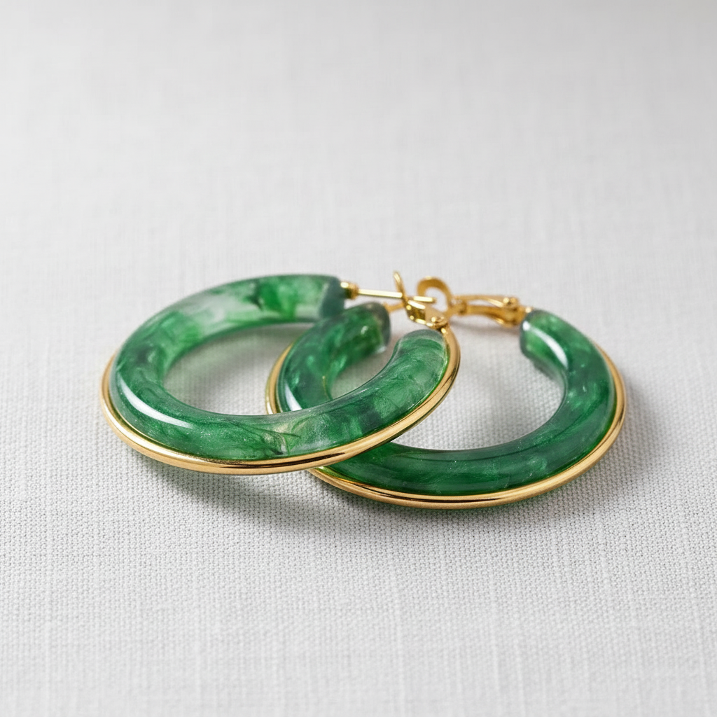 Green hoop earrings with gold accents on a light gray background