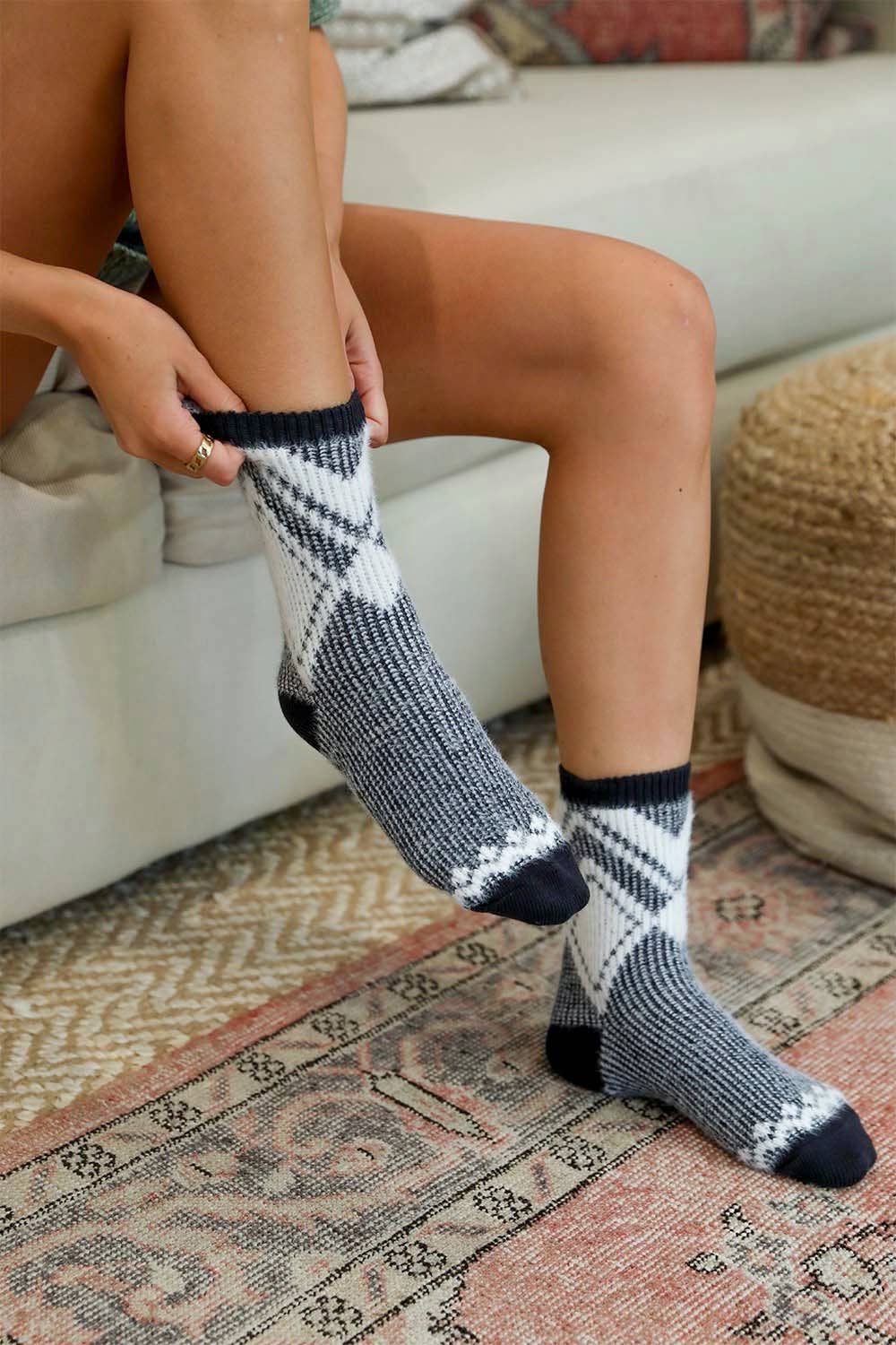 Woman wearing black diamond pattern faux mohair socks on a patterned rug.