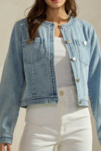 Woman wearing a light washed denim jean jacket on a neutral background