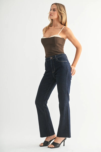 Woman wearing a strapless top and flare leg jeans in premium dark wash denim on a white background