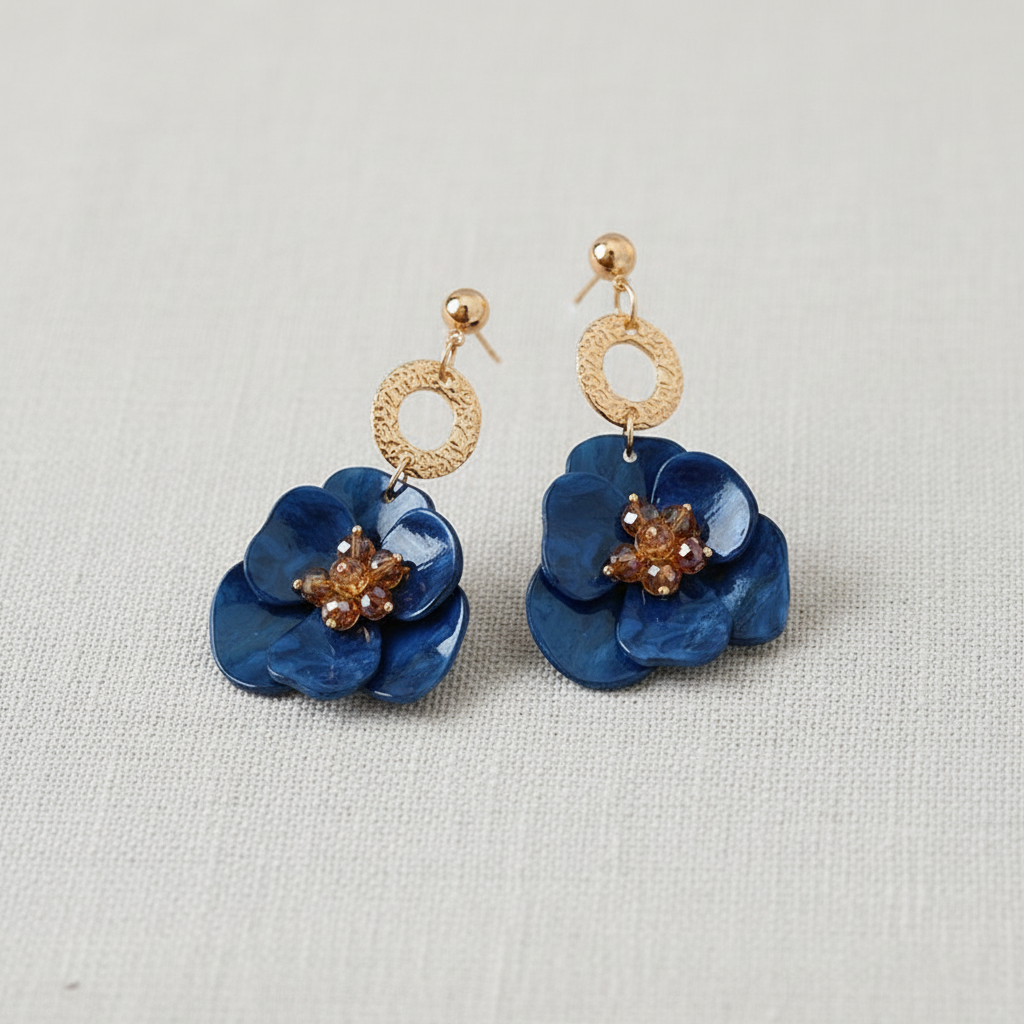 Pair of blue flower-shaped earrings with gold accents on a light gray background