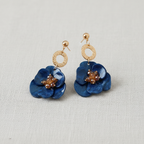 Pair of blue flower-shaped earrings with gold accents on a light gray background