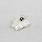 Pearlized flower drop earring with a dark gray pearl on a light gray background