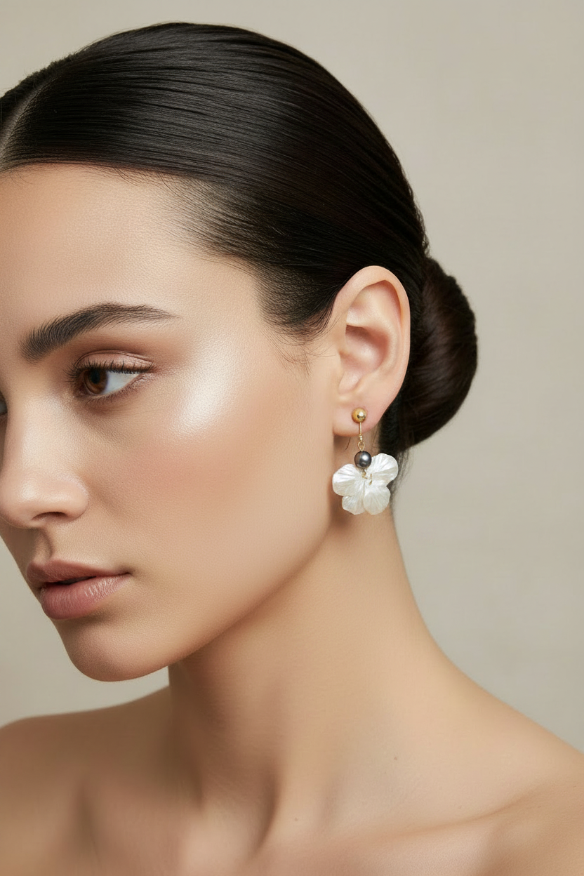Woman wearing flower dangle dark gray pearl accent earrings against a neutral background