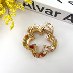 Gold and multicolored flower-shaped hair clip on a white surface 