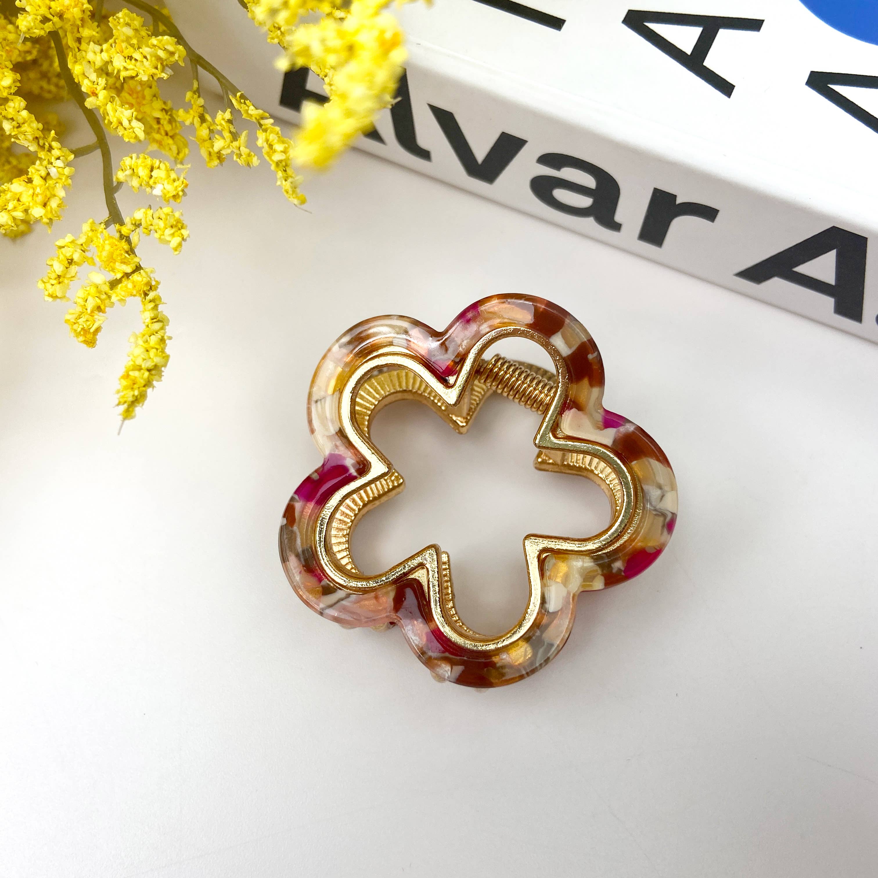 Decorative hair clip with flower design and pink color combinations on a white surface