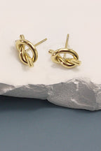 18k gold-plated stainless steel knot earrings on a stone surface