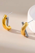 Gold and silver tone criss cross hoop earrings on a white background