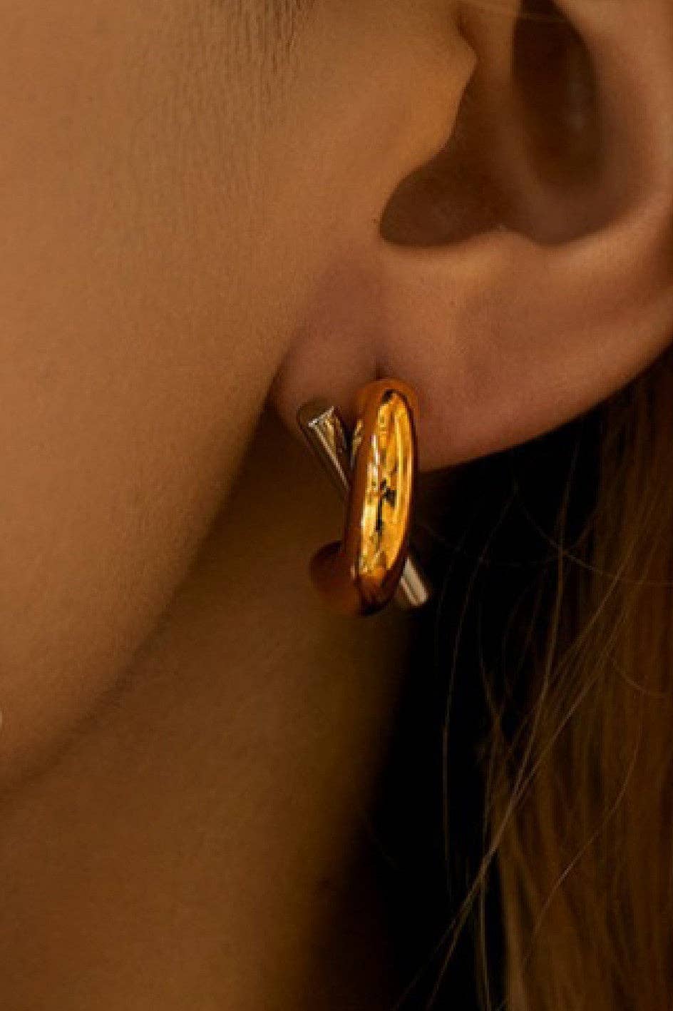 Woman wearing gold and silver two tone criss cross earrings