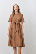 Woman wearing a brown corduroy tiered dress against a white background