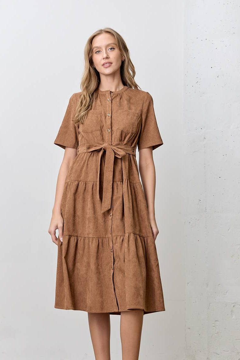 Woman wearing a brown corduroy tiered dress against a white background